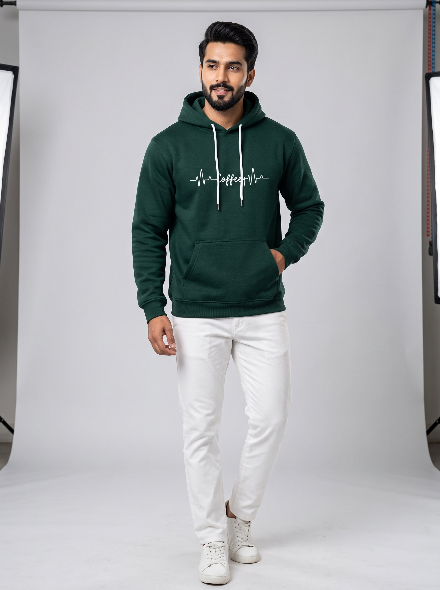Full body shot of a man wearing a dark green hoodie with a white coffee heartbeat print and white pants.