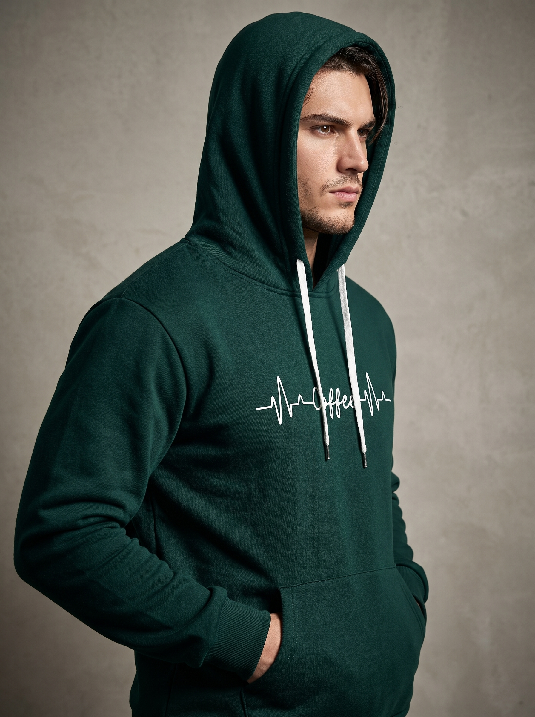 Close up of a man wearing a dark green hoodie with the hood up, showing the white coffee heartbeat print.